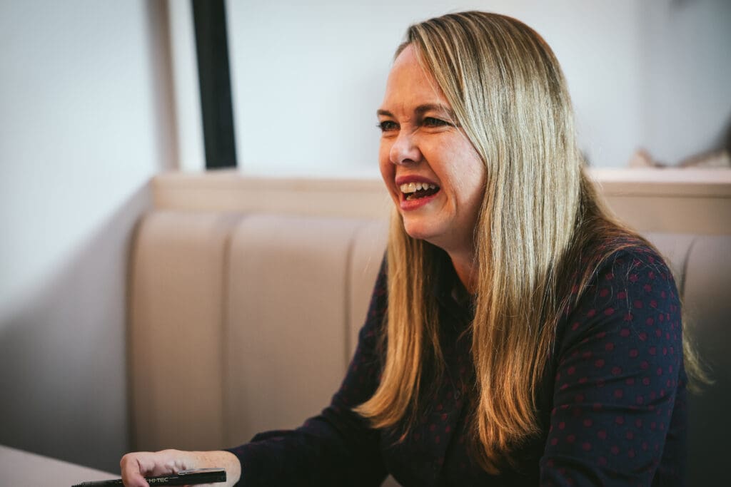Melinda McDougall, holding a pen, happy