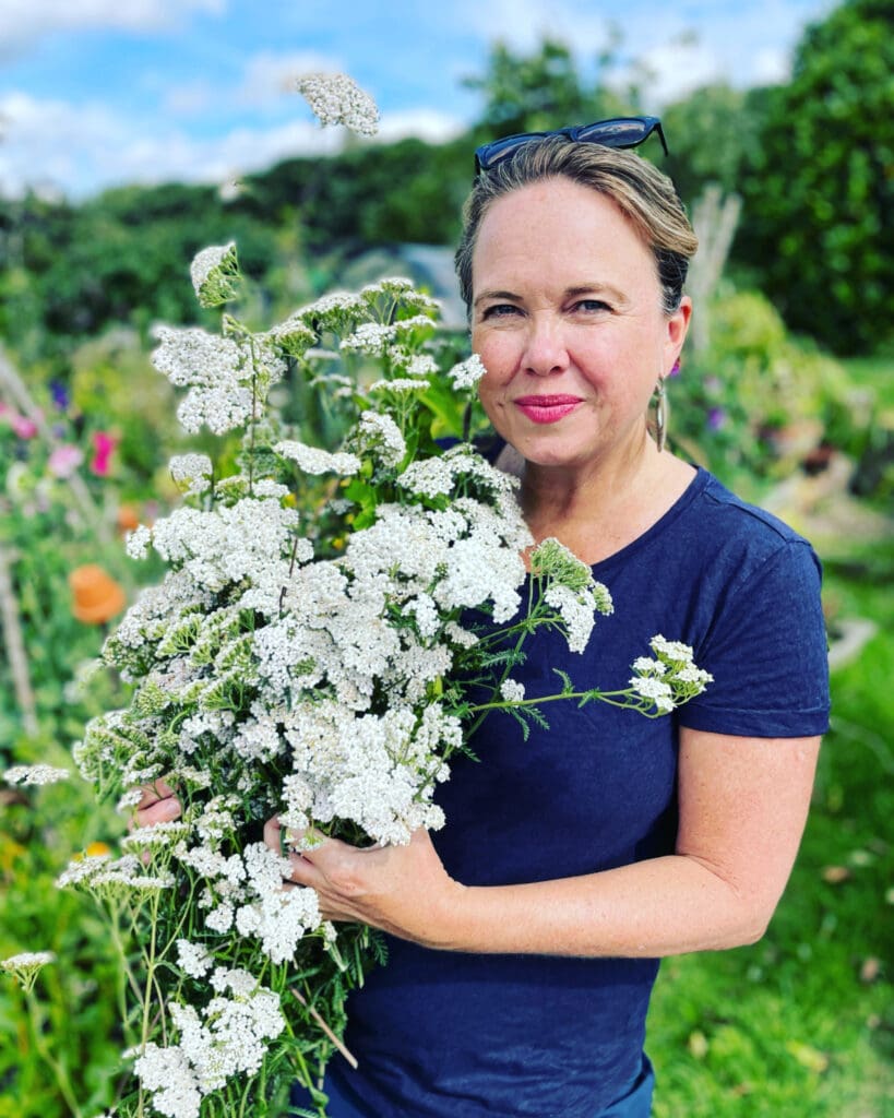Melinda, wearing blue shirt holding yarrow flower